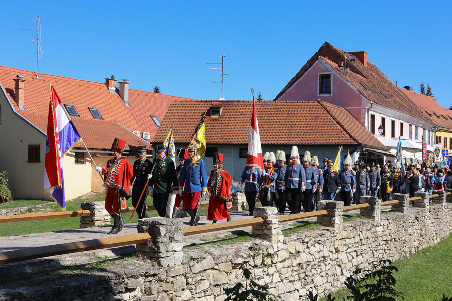 Uniformierte Gruppen marschieren mit Fahnen durch Varaždin