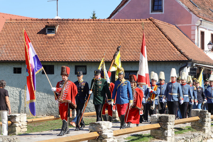 Uniformierte Gruppen marschieren mit Fahnen durch Varaždin